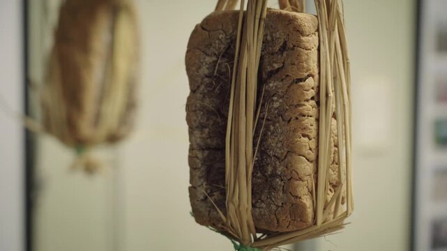 A close-up of a dried meju fermented soybean block hanging or placed in a traditional Korean food preparation setting.