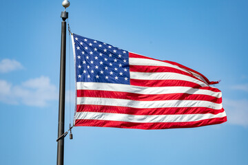 Obraz premium American flag with stars and stripes waving in the wind against a bright blue sky symbolizing freedom patriotism and the United States