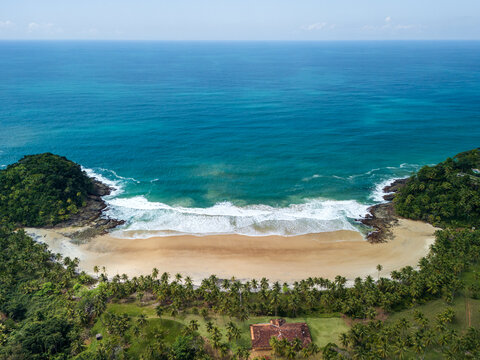 Aerial view of the pristine sandy beach at Itacare, surrounded by lush tropical vegetation, rocky headlands, and turquoise ocean waters in Itacare, State of Bahia, Brazil.