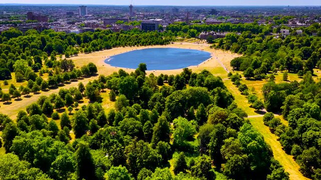 Aerial view of Round Pond in Hyde Park, London, framed by parkland on a sunny summer day; ideal for travel promotion, tourism, editorial, and urban design use