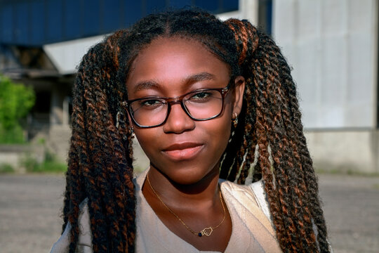 Fabulous outdoor portrait of a beautiful Black woman with glasses and stylish twisted pigtails hairstyle