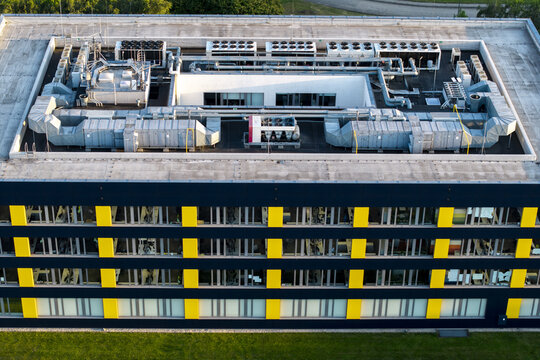 Aerial view of AI Data Center Buildings featuring complex HVAC systems on the rooftop of a modern building with a yellow and black facade in Krakow, Lesser Poland Voivode, Poland.