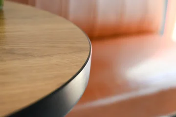 close up detail of a round wooden tabletop with black metal edge © sutichak