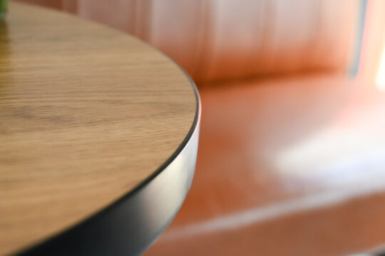 close up detail of a round wooden tabletop with black metal edge