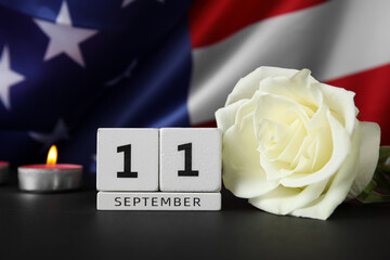 Obraz premium Calendar with rose flower and burning candle on black table against USA flag. National Day of Prayer and Remembrance for the Victims of the Terrorist Attacks