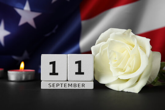Calendar with rose flower and burning candle on black table against USA flag. National Day of Prayer and Remembrance for the Victims of the Terrorist Attacks