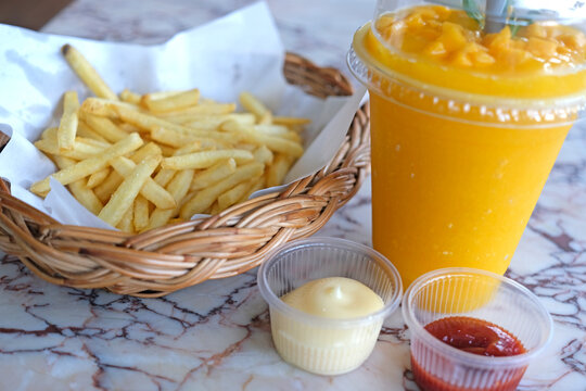 Golden french fries served with dipping sauces and a refreshing orange smoothie