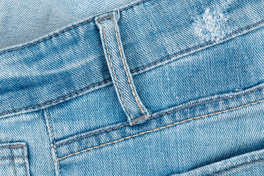 Blue jeans texture with belt loop and stitching detail. Macro view of denim fabric. Casual clothing material for fashion design. Durable cotton textile garment for everyday wear