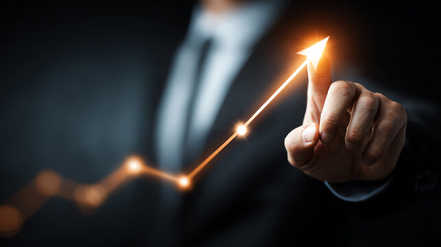 A businessman pointing at a glowing graph indicating upward growth and success in a dark background.