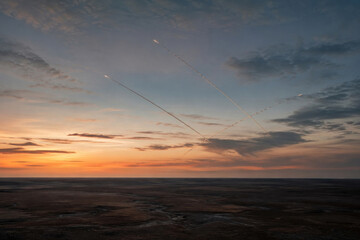 Fototapeta premium Multiple Missiles Crossing Twilight Sky Over Barren Landscape