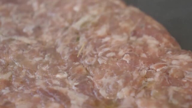 A detailed macro shot of fresh, raw ground Italian sausage seasoned with herbs and spices. This footage captures the juicy texture of the meat before it is added to a pizza or used in authentic Italia