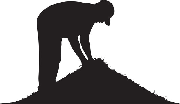 Silhouette of a person standing on a grassy mound, bent over