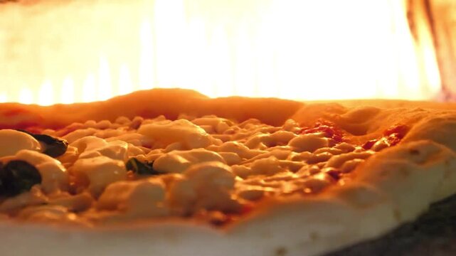 Cinematic close-up of a fresh Italian pizza baking inside a rustic wood-fired brick oven. The footage features bubbling mozzarella cheese and a rising crust against a backdrop of vibrant, glowing oran