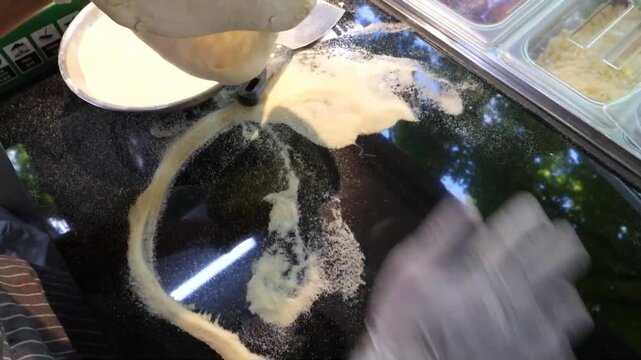 Close-up of a professional chef wearing gloves, skillfully kneading and stretching raw pizza dough on a black granite countertop covered in flour. This footage highlights the traditional Italian artis