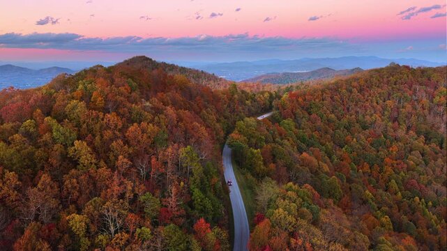 Car drive during road trip in evening time on scenic parkway in full autumn splendor. Mountain highway lined with brilliant red, orange, and gold foliage.