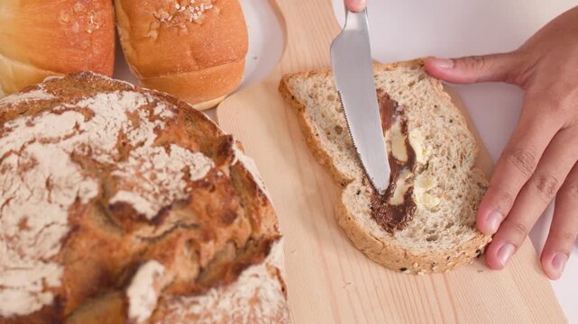Spreading Peanut Butter on Multigrain Bread Slice with Assorted Bakery Loaves