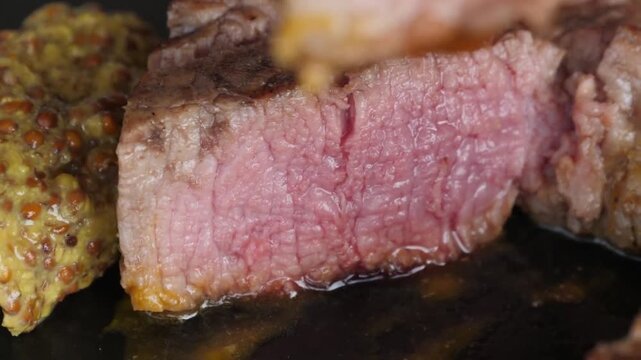 A high-quality close-up shot of a tender and juicy slice of medium-rare beef steak being held up by a fork. The meat shows a perfect pink center and a seared outer crust.