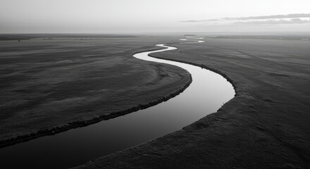 Fototapeta premium A serene river flows gently through a vast, dark landscape under a cloudy sky.