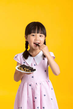 Portrait of a young girl biting a roasted seaweed roll while holding a full plate