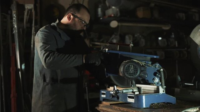 White male fabricator cutting metal on miter saw with protective gloves and goggles, sparks and dust, focused maintenance scene