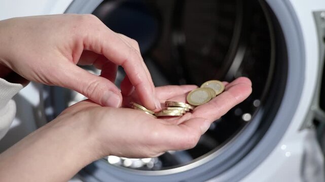 Expensive laundry services. Woman's hand counts coins in front of a washing machine, symbolizing the expensive laundry service