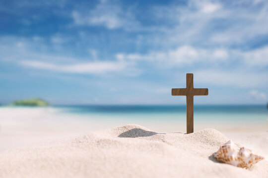 Seashells and the Cross of Jesus Christ on a sandy beach, background for church summer camps, summer Bible school, and summer retreats
