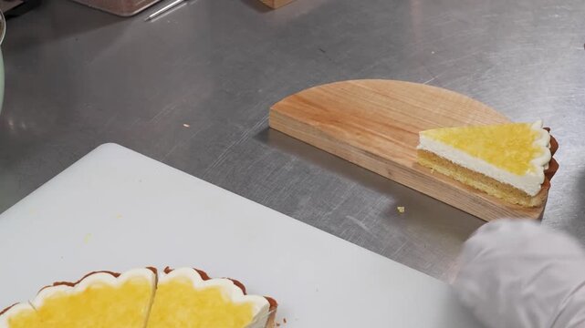 professional close-up shot of a delicious citrus tart featuring a buttery shortcrust pastry, tangy lemon curd filling, and a smooth layer of whipped cream. The footage shows the dessert being plated o