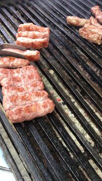 Chef using tongs to arrange traditional kebabs on a barbecue grill, close up