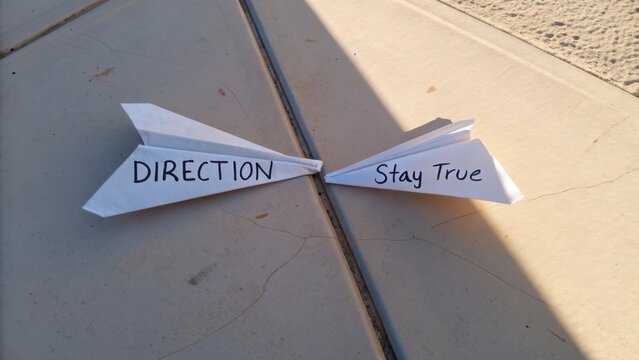 Paper airplanes with motivational messages on a stone surface, symbolizing focus and perseverance in achieving goals