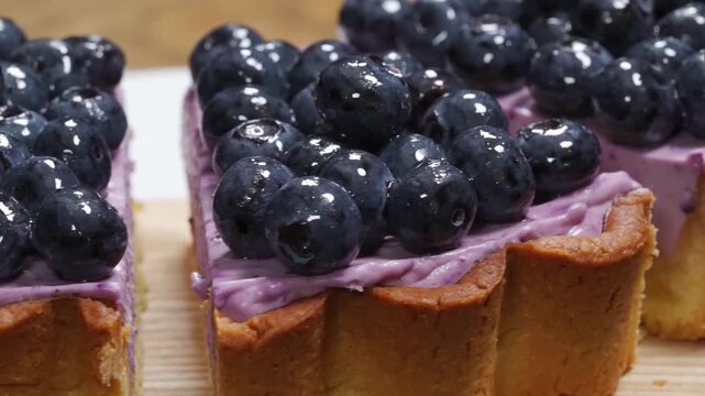 close-up shot of a decadent blueberry cream pie slice. The dessert features a crisp, golden-brown shortbread crust, a thick layer of creamy purple blueberry-infused filling, and is topped with a mount