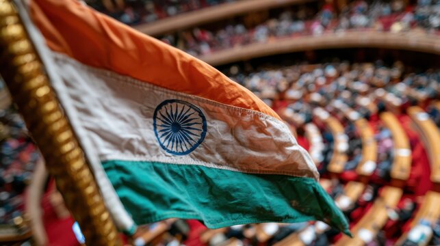 The Indian national flag waves prominently inside a large, circular legislative assembly filled with seated people.