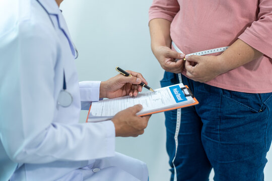 Close-up of a healthcare worker measuring an overweight woman's waist with tape, showing weight control, obesity risk, body size check, and healthy lifestyle support.