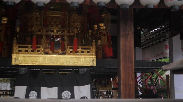 A gilded shrine altar with red lacquer pillars beneath dark wooden eaves at a traditional Kyoto temple.