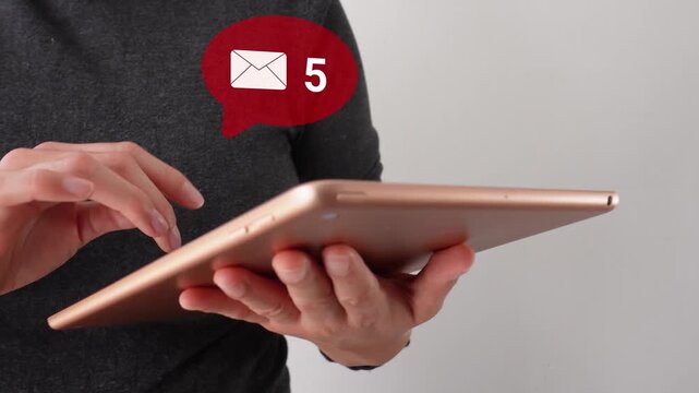 Person holds tablet with hands. Red notification bubble shows unread messages. User appears focused on device. Ideal for digital communication or productivity themes.