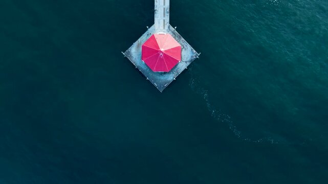 A beautiful top down view of the Huntington Beach Pier. The drone slowly soars toward the shore revealing the crashing waves of Surf City USA.