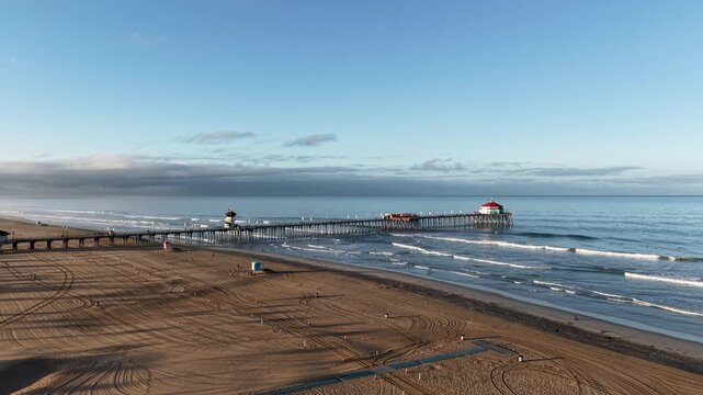 A distant Low Altitude Drone shot of the iconic Huntington Beach Pier. A beautiful view of the historic Pier stretching into blue pacific waters of Surf City USA.