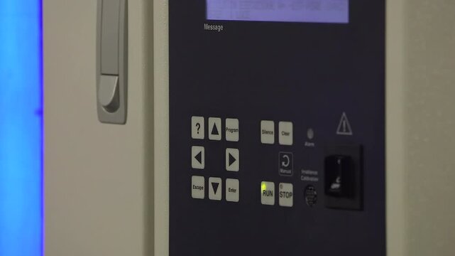 Close-up of a laboratory technician operating the control panel of a xenon test chamber used for accelerated material aging and environmental testing.