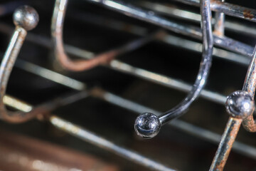 Close up of shiny metal hooks on rack with dark blurred background, showing texture and reflections on curved surfaces © CoreRock