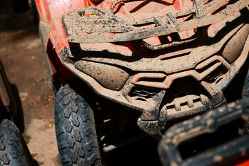 Mud covered off road vehicle front close up with rugged tire and textured dirt on body, showing adventurous outdoor activity and rough terrain exploration © CoreRock