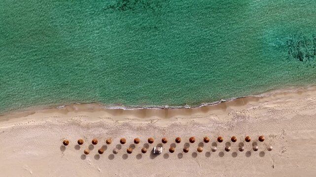 Overhead aerial of straw umbrellas at empty beach near the shore, Simos beach, Elafonisos island