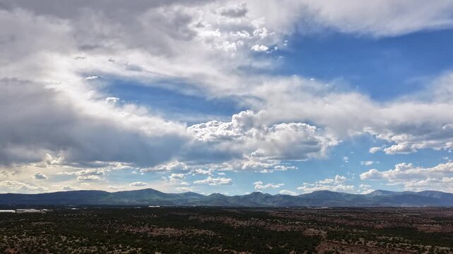 4K UHD drone timelapse capturing a dynamic sky filled with diverse cloud types shifting and morphing rapidly. Flat-topped desert mesas sit under the expansive, changing atmosphere.