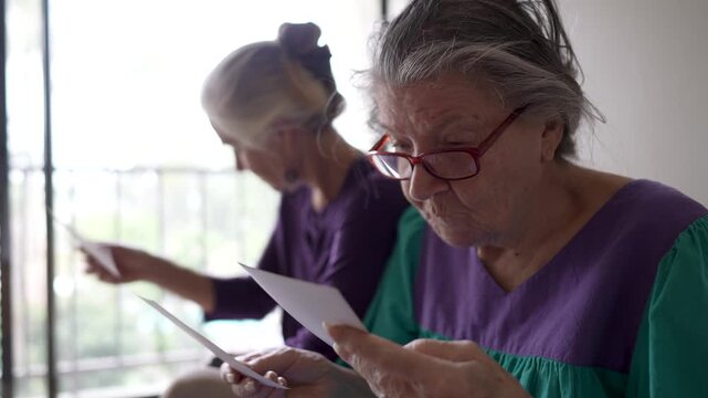 A daughter visits her mother at a senior care facility. They share stories and look at old photos together, enjoying their time.