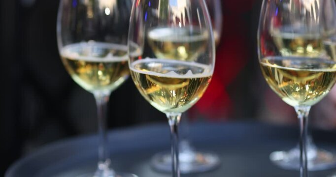 Glasses with white wine on a plate in the hands of a server.