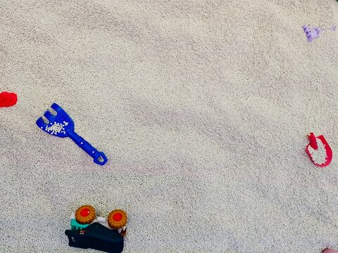 Kids summer activities concept with plastic shovel and toy car on a sandy background with copy space.
