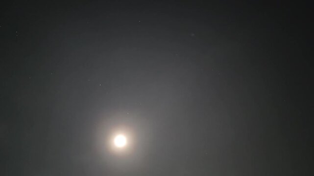 Beautiful night time lapse of glowing full moon moving across dark sky