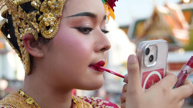 Thai Traditional Dancer Applying Red Lipstick Using Smartphone as a Mirror