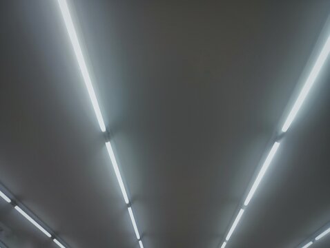 Modern minimalist interior ceiling featuring parallel linear LED strip lights with strong perspective lines and clean geometric design. Ideal for architecture, lighting technology, contemporary interi