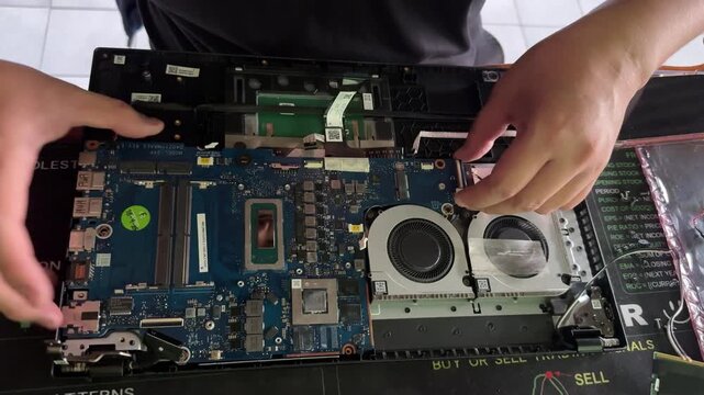 A computer repair technician is replacing a computer motherboard, which includes the circuit board and CPU chip. A close-up macro image of PC hardware.
