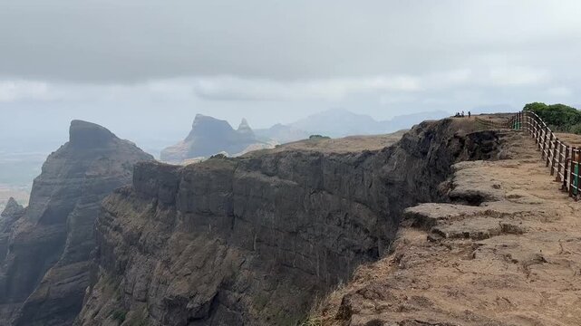 Famous Konkankada with railings during the pre monsoon season at Harishchandragad Fort, Maharashtra.