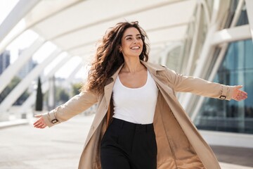 Fototapeta premium Smiling woman with outstretched arms enjoying freedom in modern city